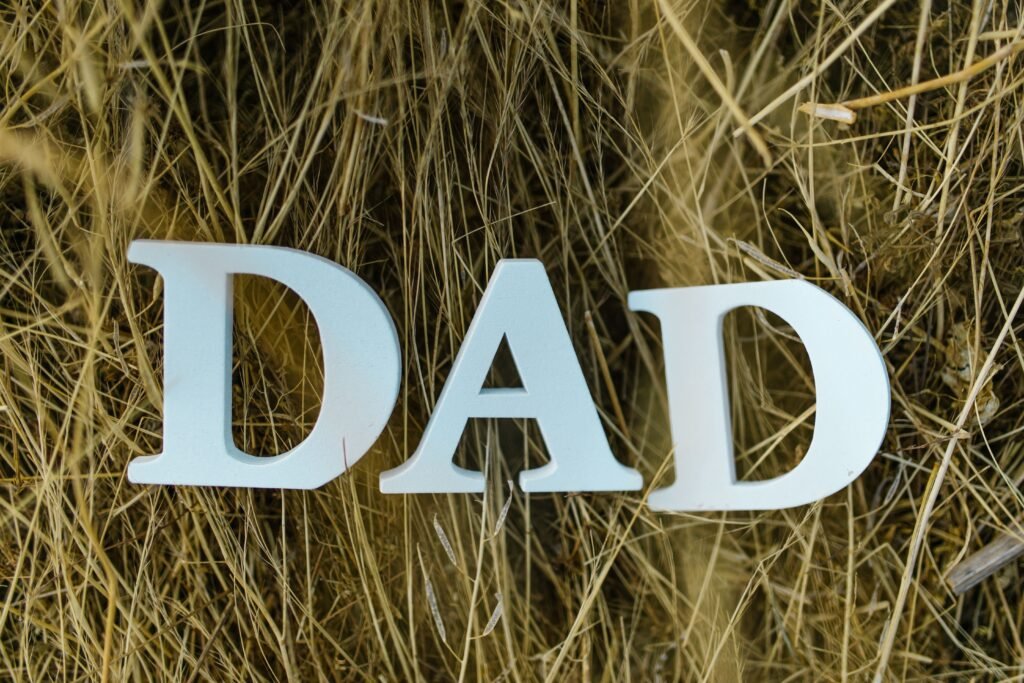 Stylized letters spelling 'DAD' set against a background of rustic hay, perfect for Father's Day themes.